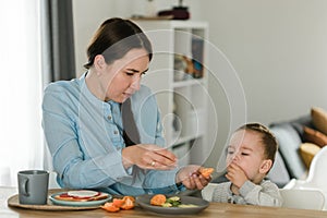 Young mother feeding her baby son with fruit