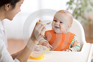 Young mother feeding her baby son with puree