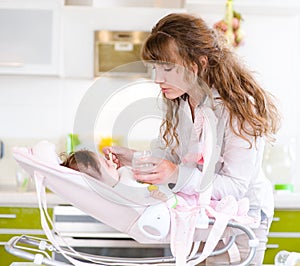 Young mother feeding her baby with a spoon