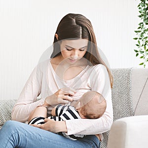 Young mother feeding her newborn child with breast milk