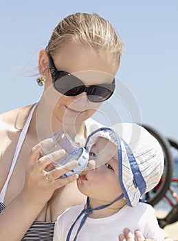 Young mother feeding her son at the beach.