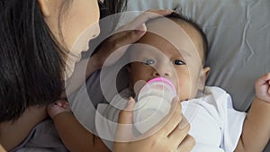 Young mother feeding milk to baby and kiss on forehead