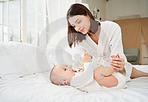 A young mother feeds her baby with baby food