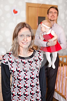 Young mother on foreground and father with baby girl on background