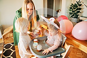 Young mother giving cupcakes to children