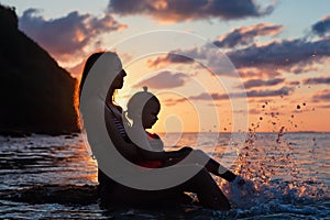 Young mother with happy daughter relax at sunset sea beach