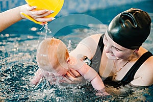 Young mother, happy little girl in the pool. Teaches infant child to swim. Enjoy the first day of swimming in water.