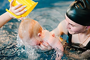 Young mother, happy little girl in the pool. Teaches infant child to swim. Enjoy the first day of swimming in water. Mom holds