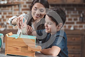 Young mother helping little son to paint a