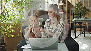 A young mother helps her daughter in an online music class