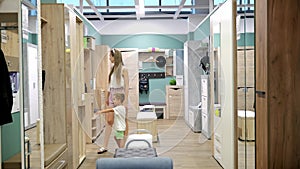 A young mother with her 3 years old son in a furniture store chooses a new hallway set. Buying modern furniture for a