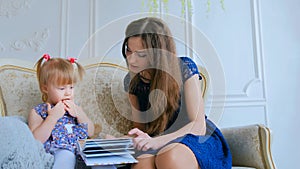 Young mother and her baby daughter looking photobook