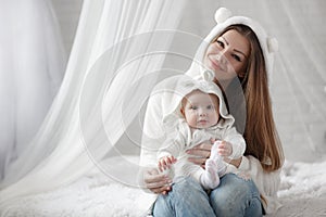 Young mother and her baby daughter playing togerher on the bed at home