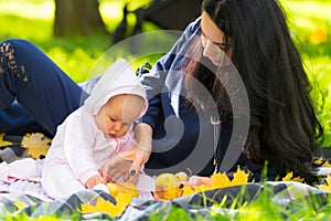 Young mother and her baby playing in an fall park.