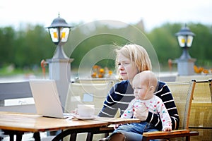 Young mother with her baby working or studying on laptop