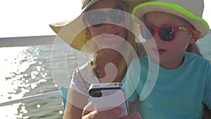 Young mother and her child are doing selfie on the boat