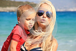 Young mother and her child playing and having fun together on the sea beach at summer vacation time. Holiday with children,