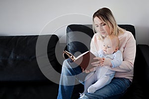 Young mother and her child reading a book, the concept of early development, indoor