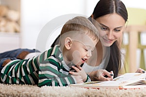 Young mother and her child son lie on the floor and reading book