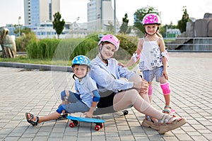 Young mother and her children son and daughter on skates in the park