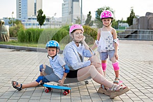 Young mother and her children son and daughter on skates in the park