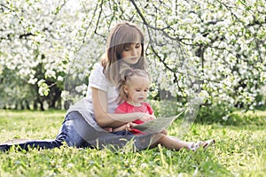 Young mother and her cute daughter reading book