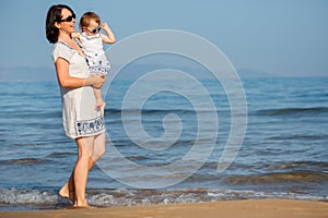 Young mother and her cute little baby girl playing on a beautiful tropical beach