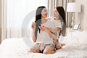 Young mother and her daughter on bed at home