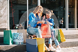 Young mother and her daughter doing shopping together. woman with girl child after shopping in street. woman with daughter with