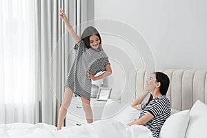 Young mother and her daughter having fun in bedroom