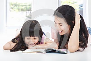 Young mother and her daughter reading book