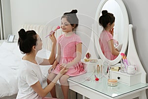 Young mother and her daughter spending time together in bedroom