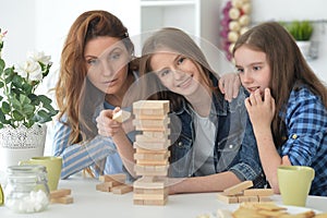 Young mother and her daughters playing with a wooden blocks