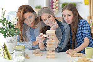 Young mother and her daughters playing with a wooden blocks