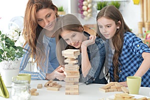 Young mother and her daughters playing with a wooden blocks