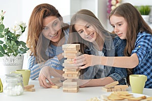 Young mother and her daughters playing with a wooden blocks