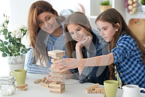 Young mother and her daughters playing with a wooden blocks