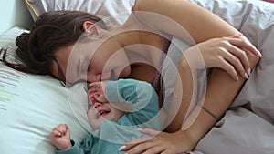 young mother and her infant baby having fun playing in bed morning cuddling