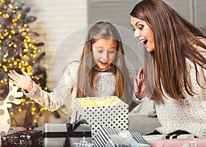 Young mother and her ittle daughters opening a magical Christmas