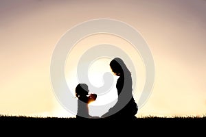 Young Mother and her Little Child are Talking Outside at Sunset