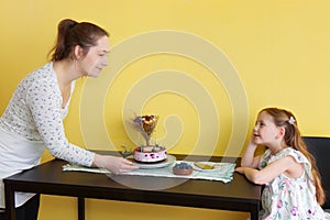 A young mother and her little daughter celebrate at home and enjoy a blueberry cake