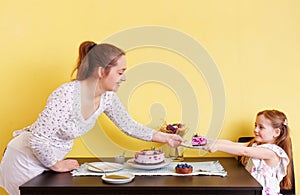 A young mother and her little daughter celebrate at home and enjoy a blueberry cake