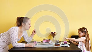 A young mother and her little daughter celebrate at home and enjoy a blueberry cake