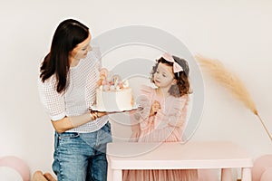 A young mother and her little daughter celebrate their birthday with a cake.