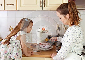 Young mother and her little daughter decorating a blueberry cheesecake.