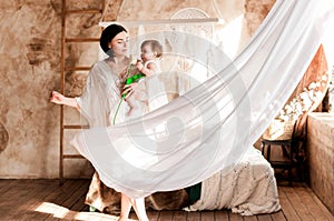 Young mother with her little daughter in her arms opposite the window