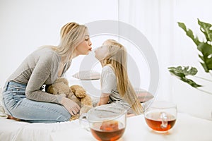 Young mother and her little daughter hugging and kissing on bed