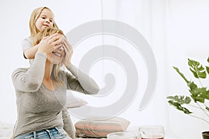 Young mother and her little daughter hugging and kissing on bed