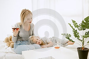 Young mother and her little daughter hugging and kissing on bed