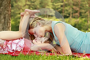 Young mother and her little daughter playing on grass